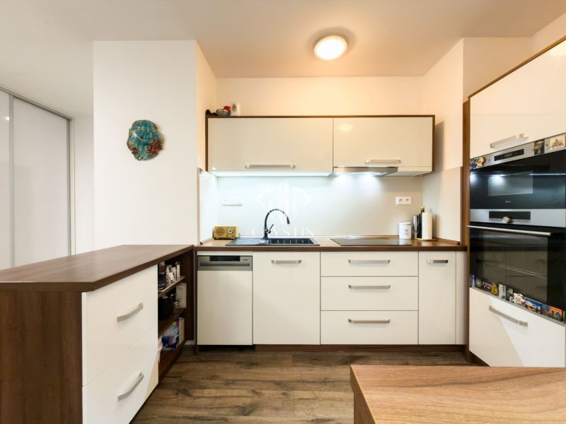 A kitchen with white cabinets, a wooden decor floor, in a 3-room apartment.