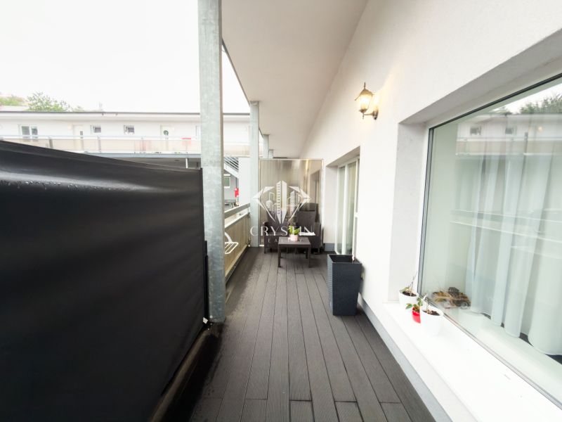 Balcony of a 3-room apartment with a wooden decor floor and outdoor seating.
