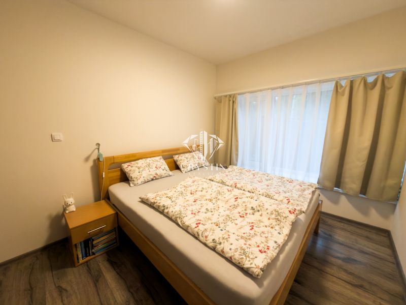 A bedroom in a 3-room apartment with a bed, curtains, and a floor with a wooden decor.
