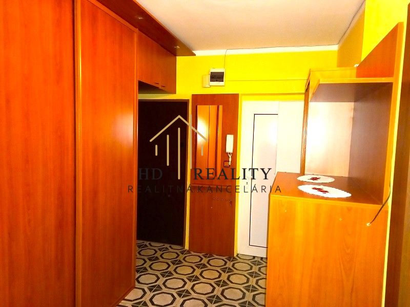 A hallway in a 4-room apartment with wooden furniture and patterned flooring.