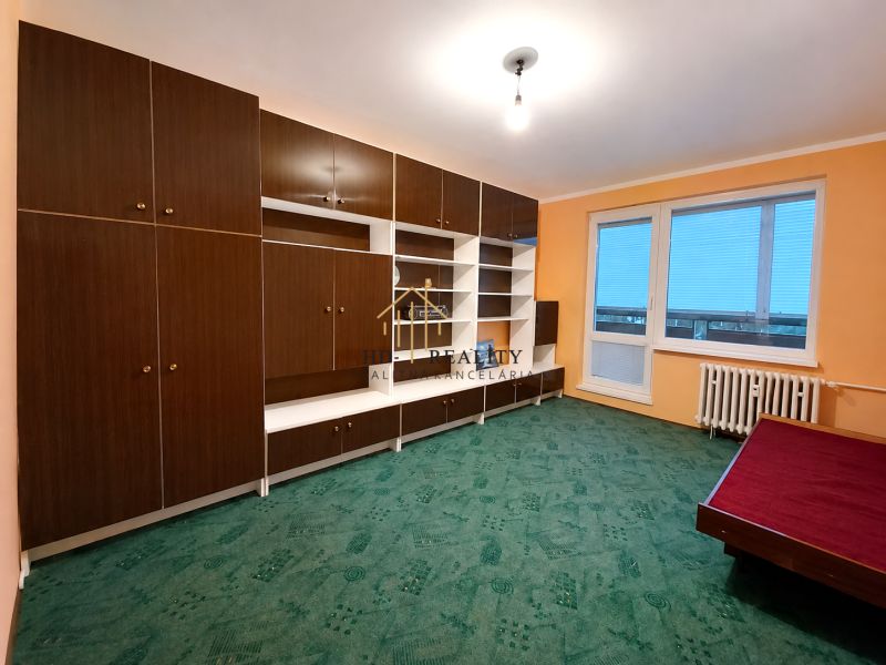 A room with a built-in wardrobe in a 4-room apartment, green carpet, radiator, large window.