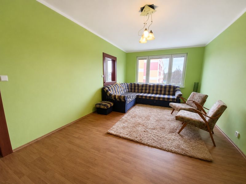 Living room in a 4-room apartment with a sofa, armchairs, and green walls; floor with wooden decor.