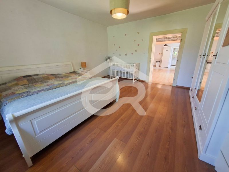 Bedroom in a family house with wood-patterned flooring, a bed, and a baby crib.