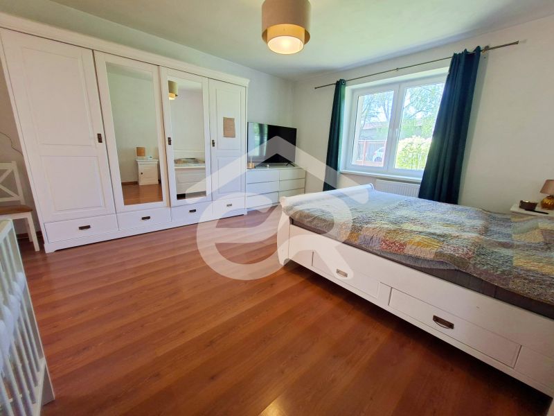 A bedroom in a family house with white furniture and a wooden decor floor.