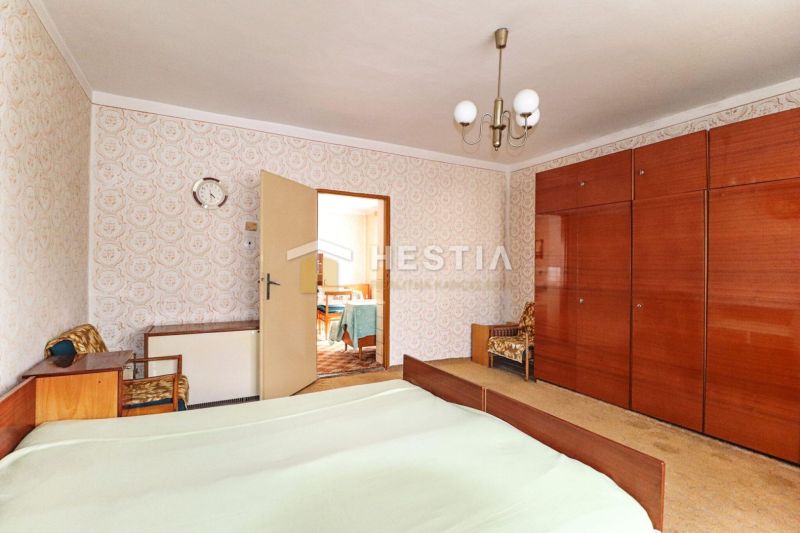 A bedroom in a family house with retro furniture and patterned wallpaper on the wall.