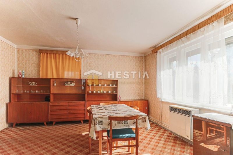 Interior of a family house with a dining table, older furniture, and a carpet.