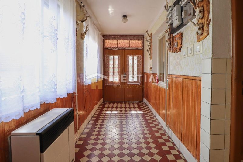 A hallway in a family house with a tiled floor and wooden wall paneling.