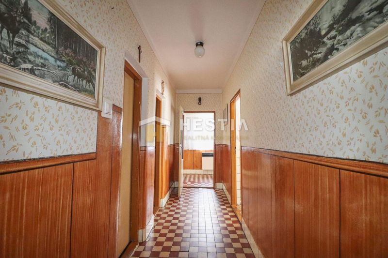 A hallway in a family house with wooden decor surfaces and patterned flooring.