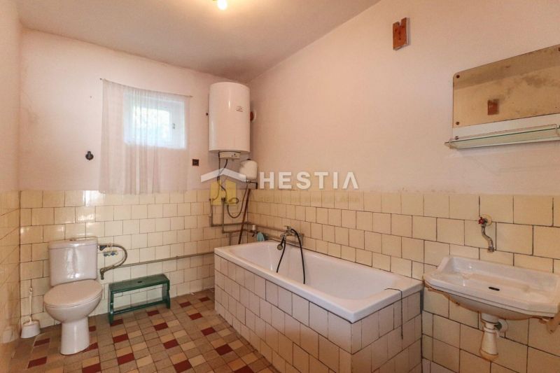 A bathroom with a tiled bathtub and a boiler in a family house.