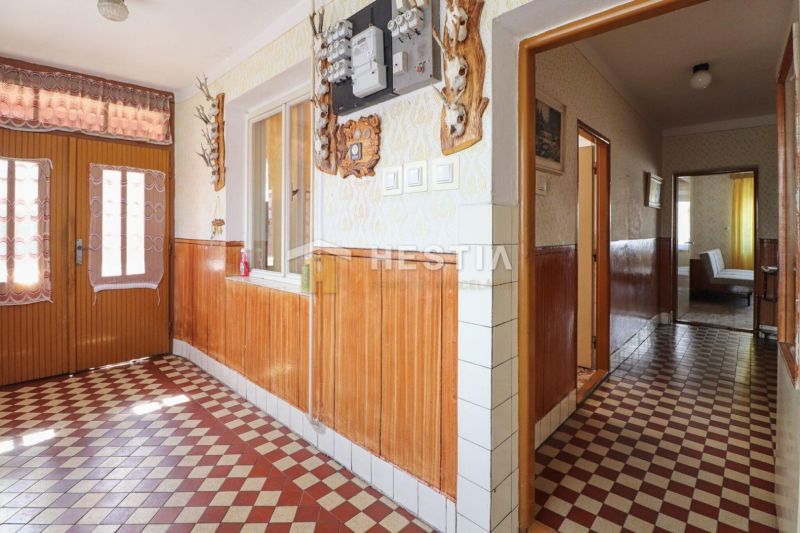 A hallway in a family house with checkered tiles and wooden wall paneling.