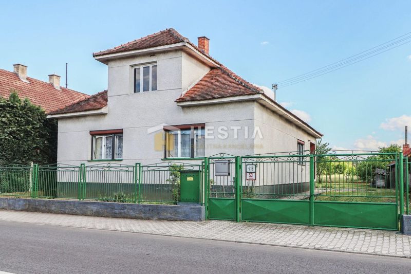 A family house in Borský Mikuláš with white walls and a green fence.