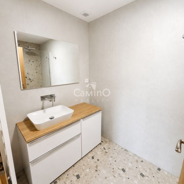 A bathroom with a terrazzo floor and wooden decor in a 2-room apartment.