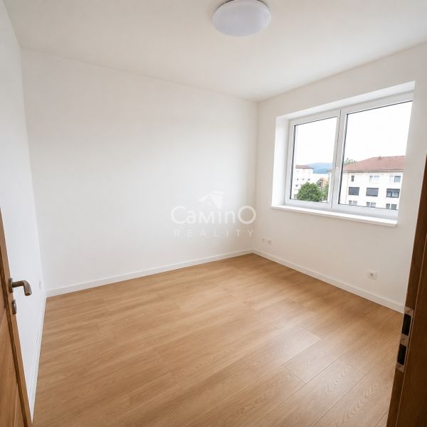 A bright room in a 2-room apartment with white walls and a wooden decor floor.