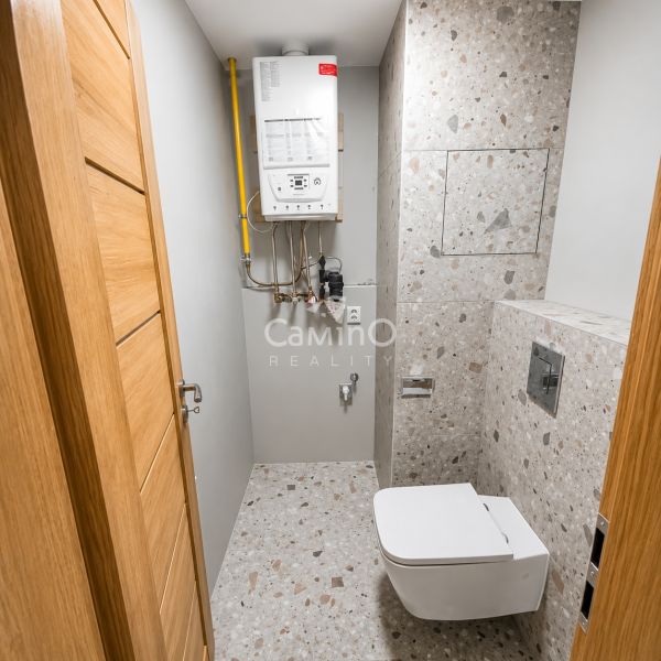 Bathroom in a 2-room apartment with a terrazzo floor and a wall-mounted toilet.