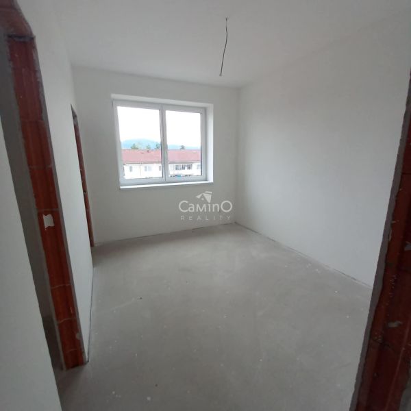 A room in a 2-room apartment with finished white walls and a large window.