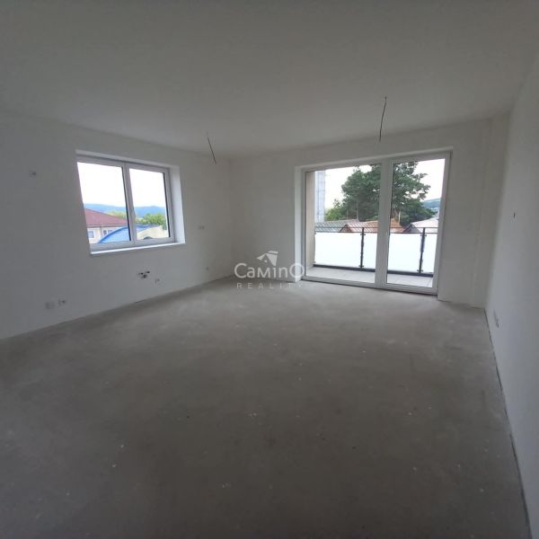 In the bright room of the 2-room apartment, there are large windows and balcony doors.