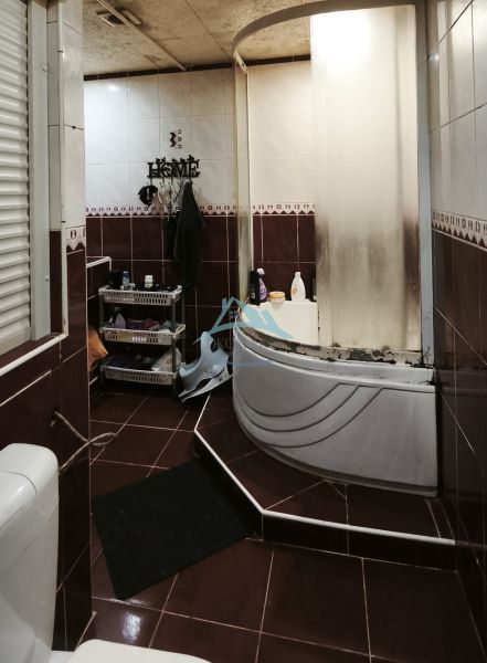 A bathroom with a bathtub, toilet, and storage shelves in a 2-room apartment.