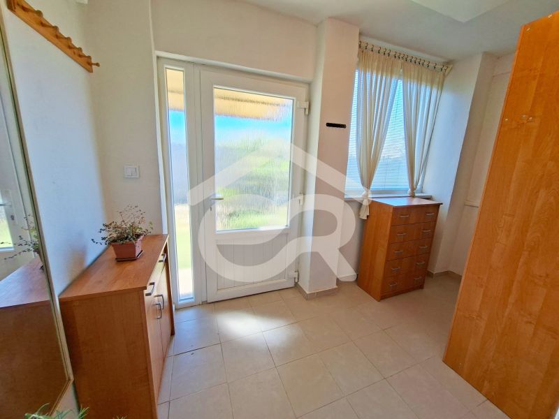 In a family house, a bright hallway with a chest of drawers, a mirror, and a plant.