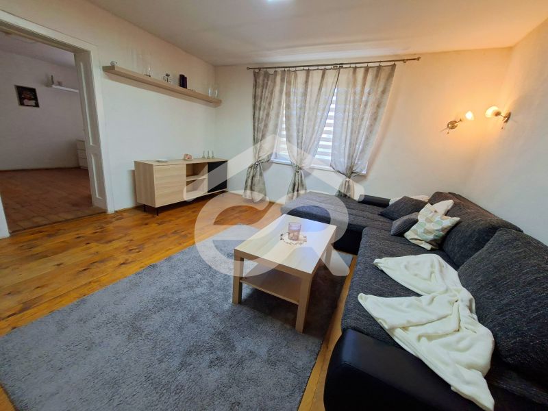 Living room in a family house with a sofa, table, wooden decor flooring, and a carpet.