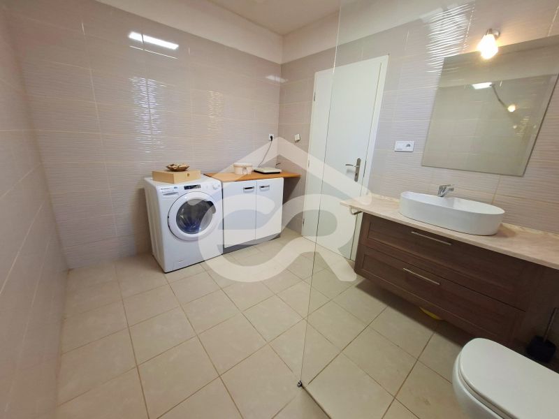 A bathroom in a family house with a washing machine, a sink, and a cabinet.