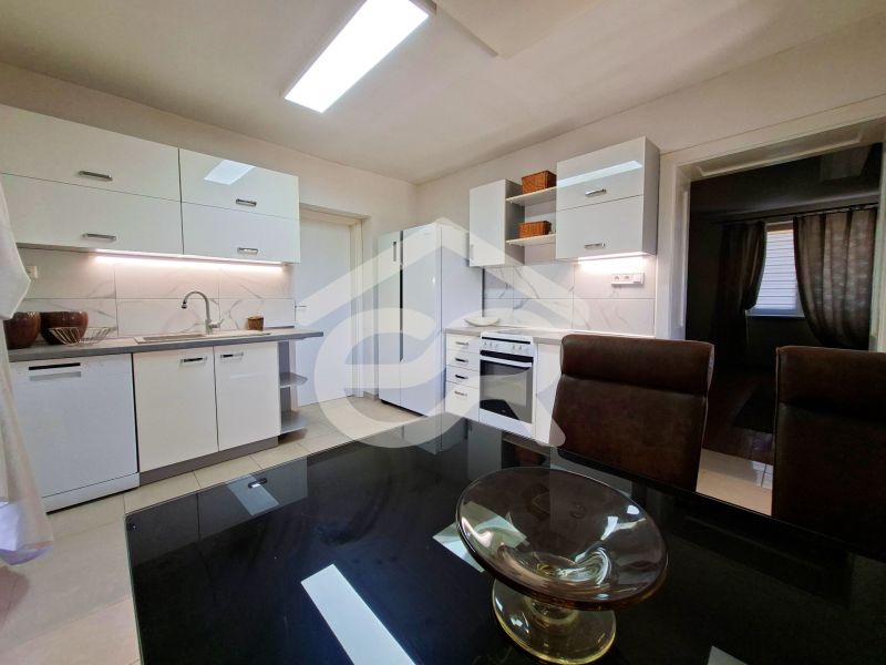 A kitchen in a family house with a light-colored kitchen unit, a ceramic hob, and a dining table.