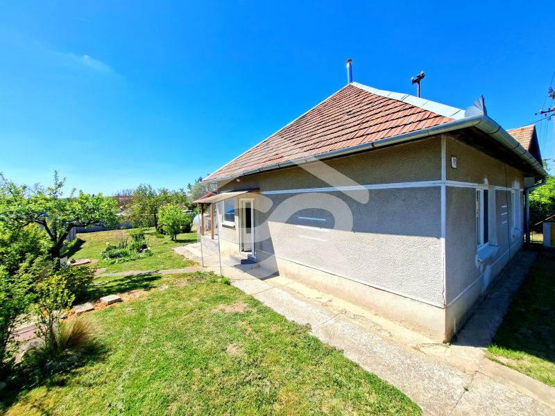 A family house in Jasová on Jasová Street with a garden, next to a sidewalk and a grassy plot.