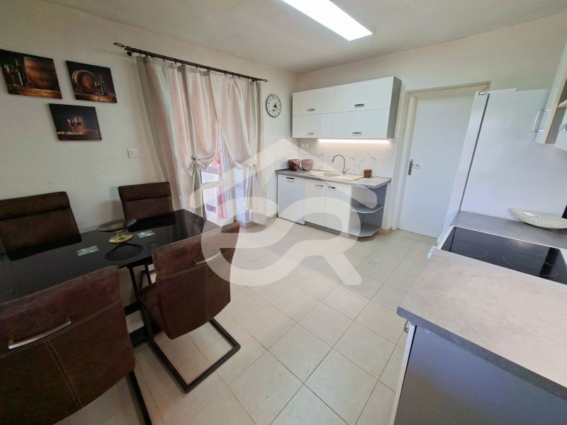 Kitchen with a dining table, kitchen unit, and paintings in a family house.