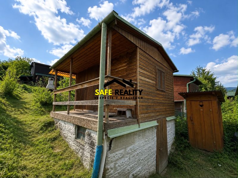 A wooden cottage in Žilina surrounded by greenery and blue sky.