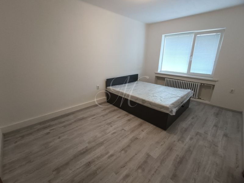 A bedroom in a 2-room apartment with a bed and a floor with a wooden decor.