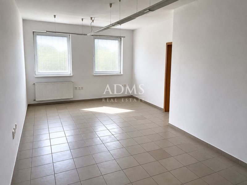 Spacious office with tiles, white walls, and two windows.