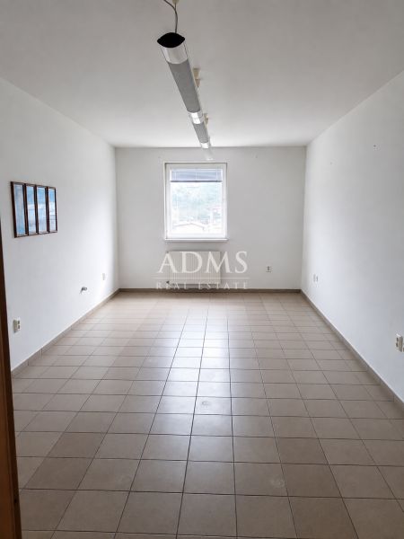 Offices with simple walls and tiled floors, central window, minimalist furnishings.