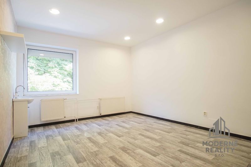An office with a large window and a wooden decor floor.