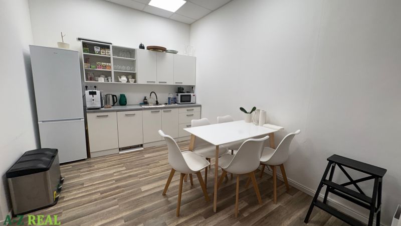 A kitchenette in commercial premises with white furniture and a wooden decor floor.