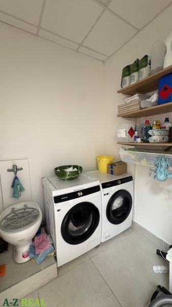 Washing machine and dryer in commercial premises with supplies on shelves.