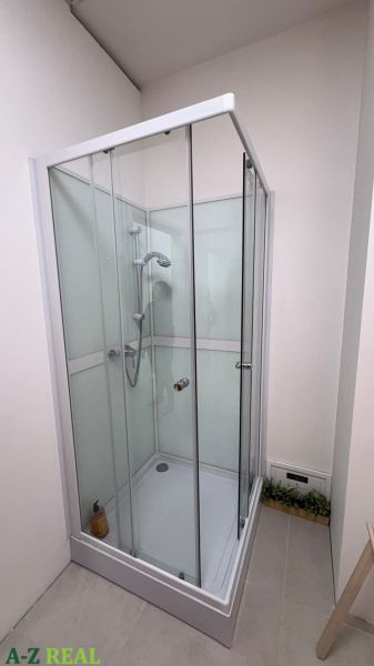 Shower enclosure in commercial premises with tiles and glass doors.