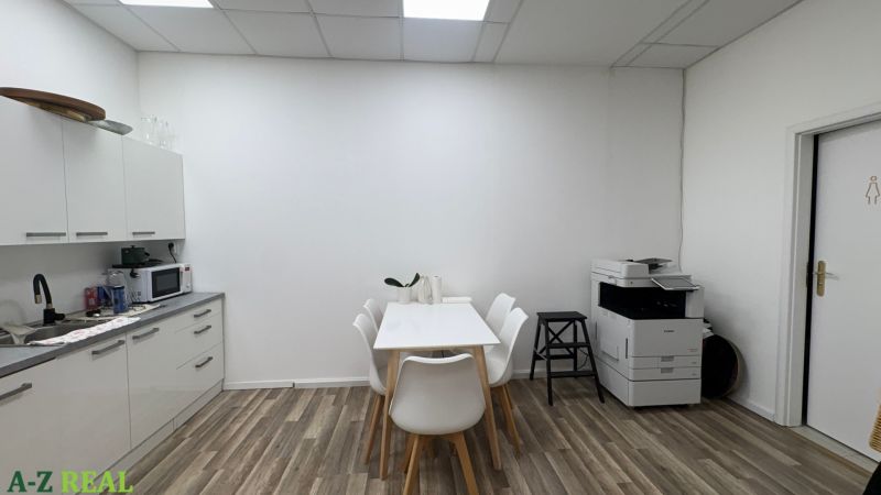 A kitchen corner with white furniture, a table, chairs, and a wooden decor floor.