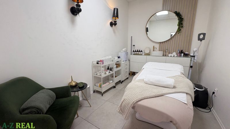 Treatment room with a bed, chair, and cosmetic products in commercial premises.