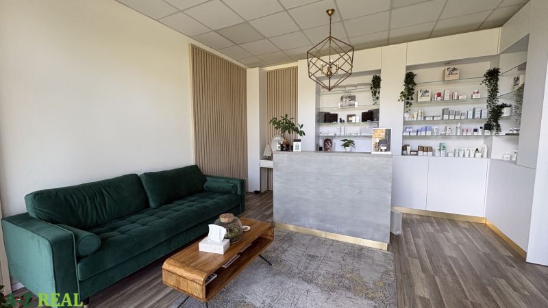 Commercial space with a sofa, reception, shelves, and a floor with wooden decor.