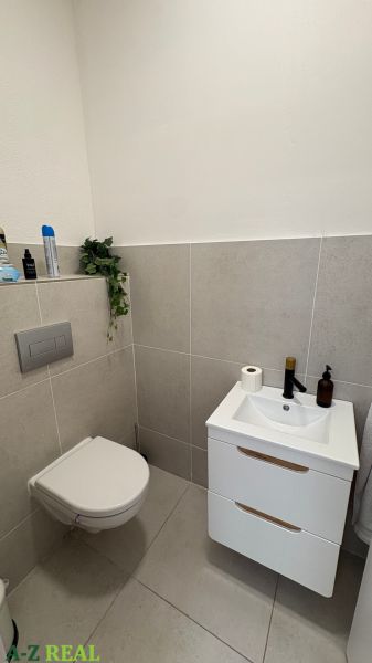 Bathroom with toilet and sink, light tiles, commercial spaces.