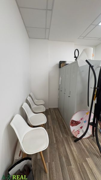 Interior of commercial space with white chairs and cabinets, floor with wooden decor.