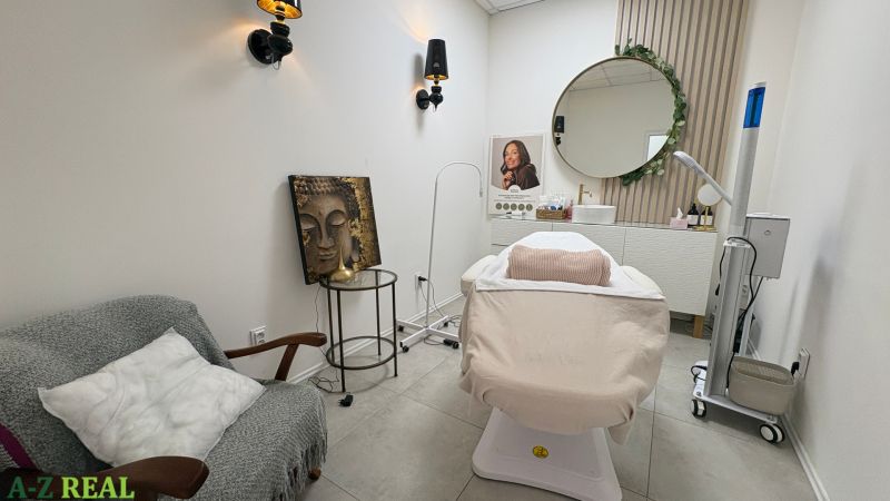 Beauty salon with a lounger, wall decorations, and a round mirror.