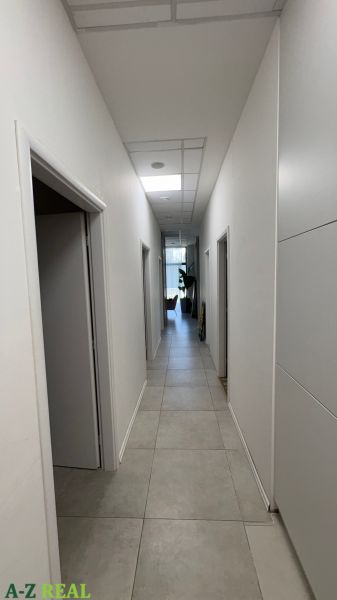 A narrow corridor with light tiles and multiple doors in commercial premises.