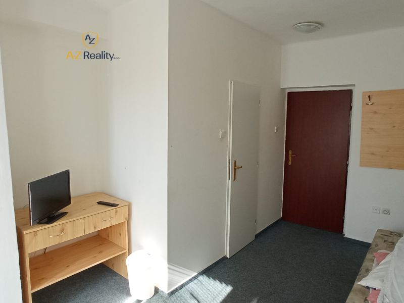 A hotel room with a television on the table and a door.
