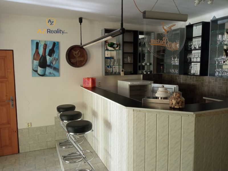 A bar counter and bar stools in an accommodation facility with glasses on the shelves.