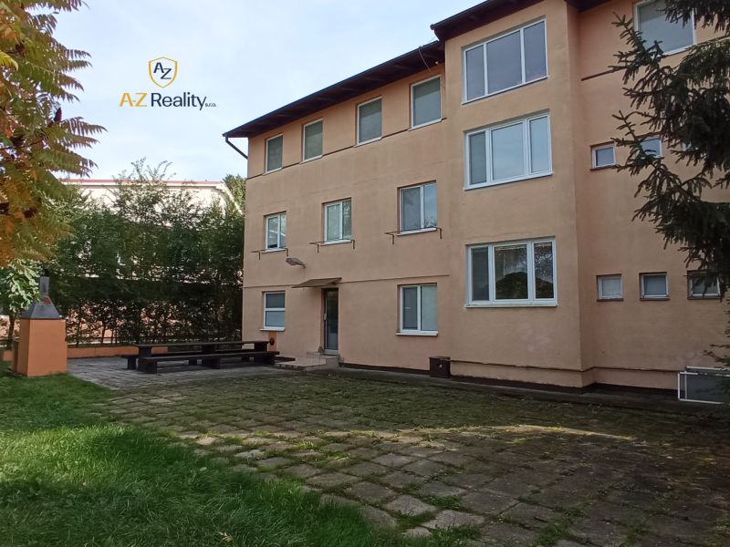 The exterior of the hotel and guesthouse buildings in Patince with a grassy area and a fireplace.