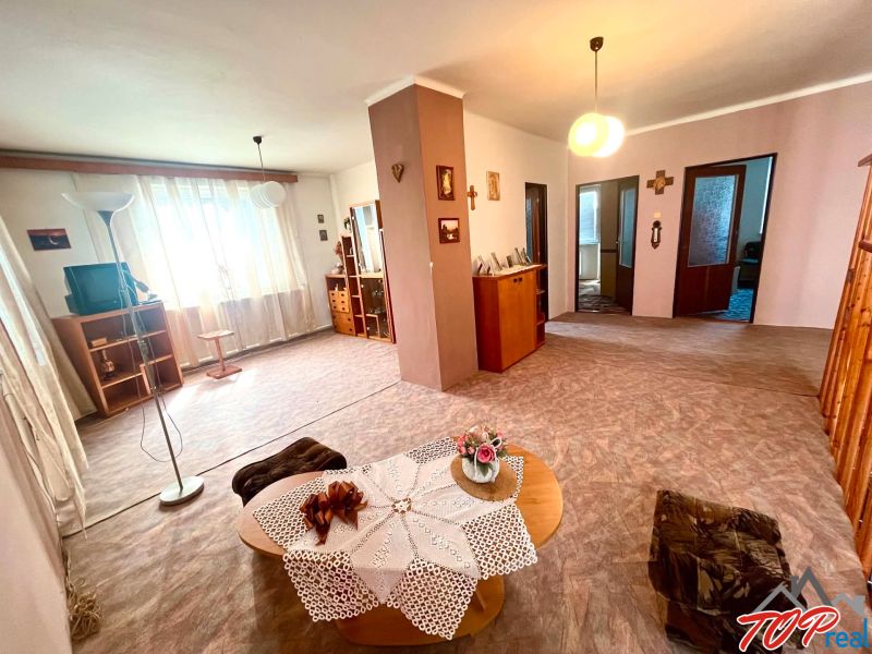 Living room in a family house with furniture, decorations, and a TV on a wooden floor.