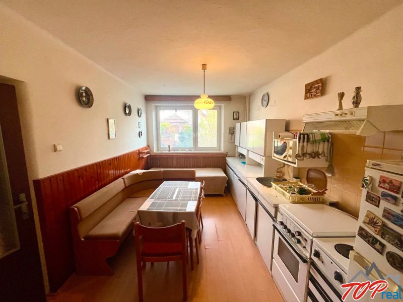 A kitchen in a family house with a corner sofa and a floor with a wooden decor.