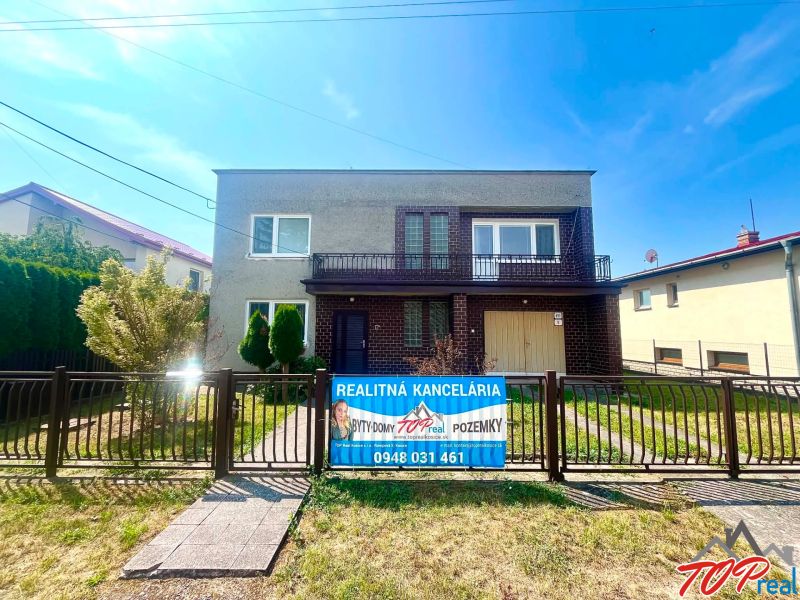 A family house on Agátová Street in Čaňa with a front garden and a real estate agency banner.