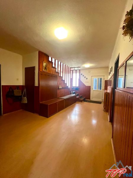 A hallway in a family house with a wood-patterned floor and wooden stairs.