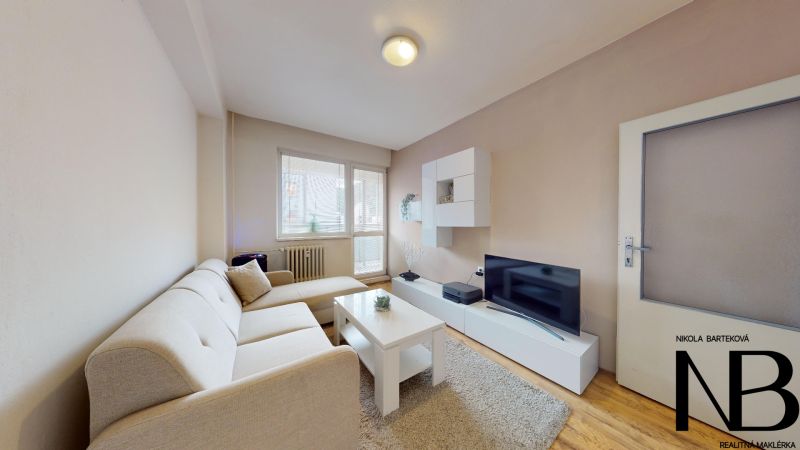 Living room of a two-room apartment on K výstavisku street with a comfortable sofa and a television.